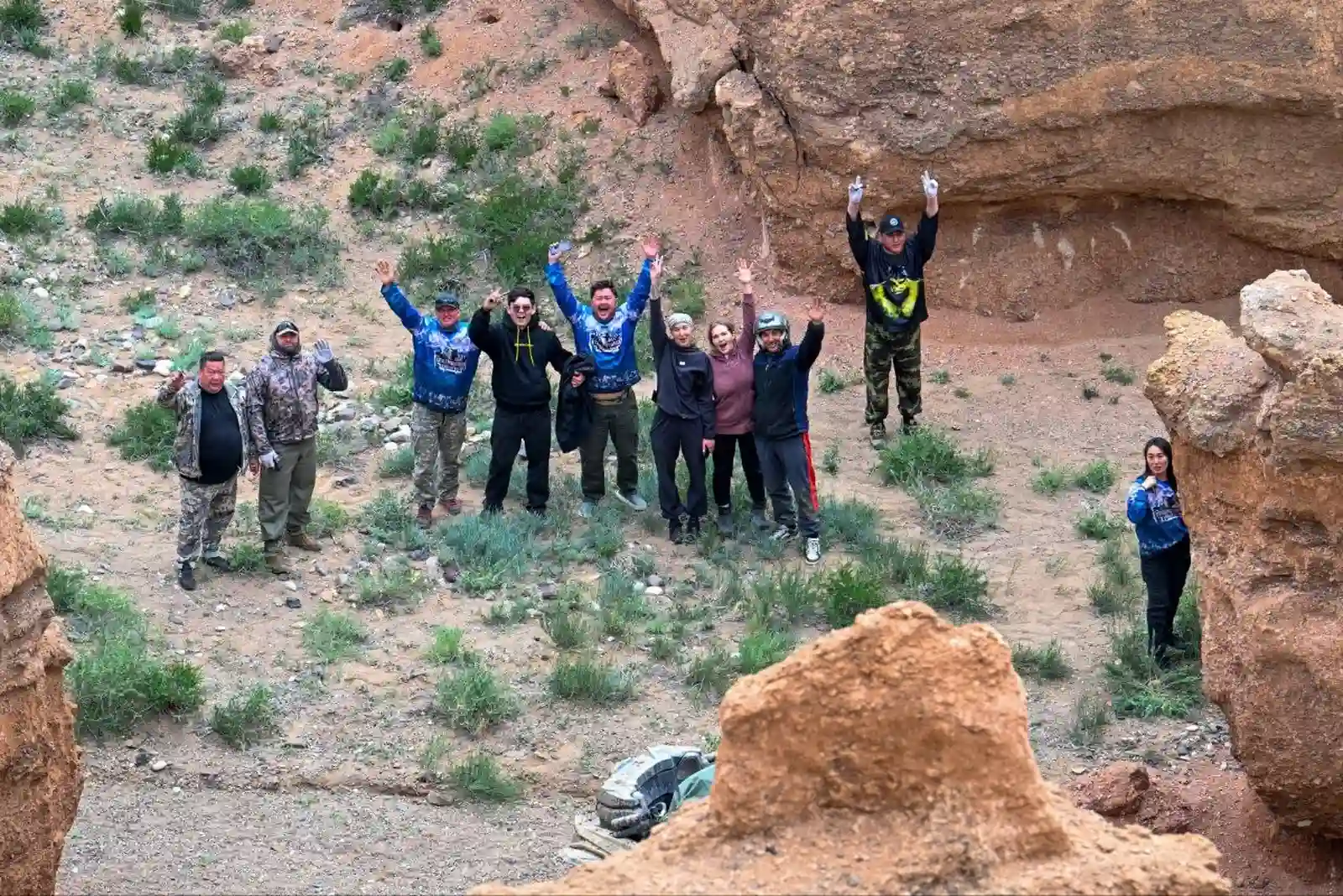 Group of tourists in helmets and buggy gear cheering among Charyn Canyon rock formations